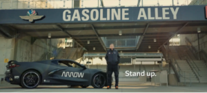 man standing in front of a business called gasoline alley next to a car with the arrow logo on it. words stand up are featured on graphic